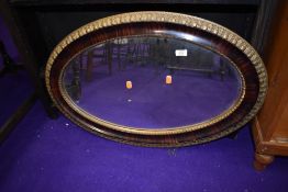 A vintage gilt and rosewood effect oval wall mirror