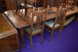 An early 20th Century dark oak wind out dining table and set of four high back dining chairs in
