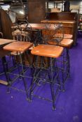 A wrought iron high table, and two matching chairs and two matching stools, having wooden seats