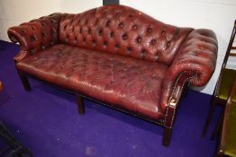 A traditional oxblood button back leather settee, having shaped back, width approx. 200cm