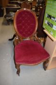A Victorian button back salon or nursing chair having scroll work frame on cabriole legs