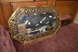 A traditional brass wall mirror having canted frame