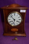 An Edwardian inlaid mahogany mantel clock having enamel dial with roman numerals and standard