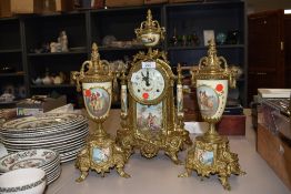 A reproduction Italian mantel clock with garnitures, having classical scenes to decorative panels.