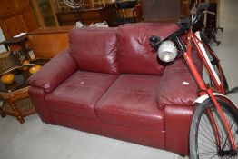 A modern maroon leatherette two seater settee