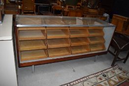 A large glazed shop display with four by four tiered internal drawers,with brass yard measure to