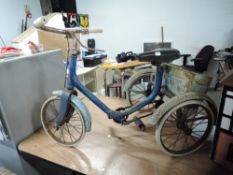 A traditional child's Trike having rubber tyres and spoked wheels and metal box to rear