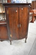 An early 20th Century oak bow fronted corner cupboard on cabriole legs height approx.139cm