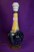 A vintage art pottery desk lamp having blue and yellow patterned glaze.