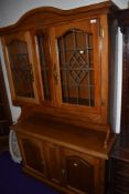 A reproduction Continental style dresser in medium stain, having lazed upper section over double
