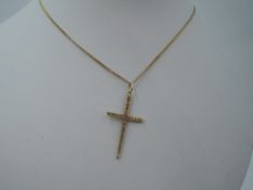 A 9ct gold cross with bark effect decoration on a gold plated chain
