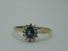 A tanzanite and diamond cluster ring of dainty form to knife blade shoulders on a 9ct gold loop,