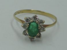 A cluster dress ring having an oval emerald style stone within a surround of cubic zirconia on a 9ct