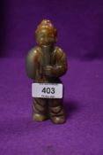 A Tibetan style figure of a monk or similar hand carved in a brown and pale green nephrite jade