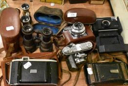 A collection of vintage cameras and binoculars including Kodak Instamatic, Kodak Synchro-Compur