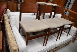 A set of four vintage teak or similar dining chairs having ply backs and upholstered seats