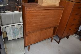 A vintage teak bureau with bookcase under having fall flap and sliding doors, width approx. 92cm