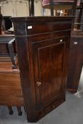 A Victorian corner cupboard having decorated veneer front with integral draw sets