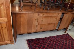 A vintage sapele sideboard of stylised form, three central graduated drawers with brass handles,