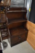 A dark stained Ercol shelf unit with cupboard under, width approx. 61cm