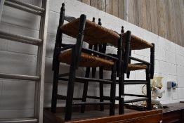 A pair of ebonised and rush seated ladder back chairs, and similar footstools