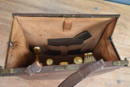 A vintage brown leather clasp top overnight/vanity bag having a set of ladies accessories to
