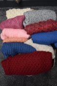 A box full of hand knitted jumpers and cardigans.