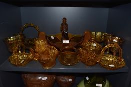 A collection of amber glass items amongst which are goblets, bowls, decorative items and more.