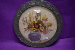 An arts and crafts style embossed metal framed dried flower display having convex glass front.
