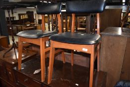 A pair of vintage dining chairs having stained frames and vinyl seats and backs