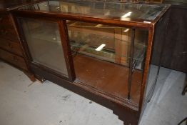 A vintage stained frame and glazed shop counter having sliding doors, width approx 137cm, some