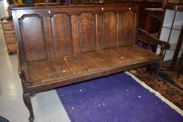 An 18th Century oak settle having five panelled back , shaped arms and cabriole legs, width