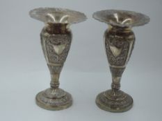 A pair of white metal bud vases having extensive floral repousse panels with plain cartouche and