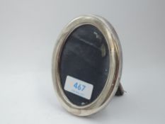 A small silver photograph frame of plain oval form having velvet easel back, Sheffield 1986, Carr'