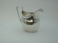A Georgian silver cream jug of plain helmet style with reeded rim and handle, London 1802, makers