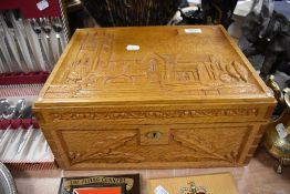A hand carved oak writing slope or case having church scene and oak leaves to front and sides in a