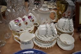 A mixture of cups and saucers and a tea pot,various designs and styles.