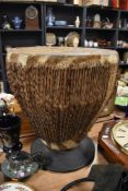 A large tribal African drum having Zebra hide and strung skin on footed base