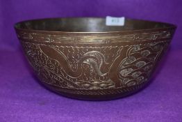 A brass singing bowl having cast Chinese characters to bottom and chased design of dragons and