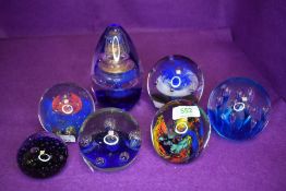 A selection of art glass paper weights including bubble swirl and floral designs in blue tones