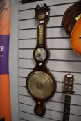 A large antique banjo barometer having mirror and inlaid detailing and scrolled finials to top.