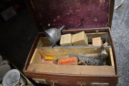 A vintage suitcase containing a selection of tools, tins, funnel and more.