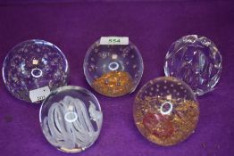 A selection of art glass paper weights in clear and gold designs