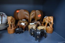 A group of wooden elephants or varying colour,size and style.
