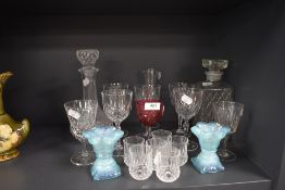 A selection of glasses and two decanters also included are two blue vaseline glass candle sticks.