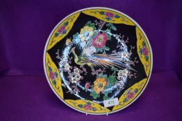 A vintage oriental plate having yellow and black ground with Chinese pheasant of similar bird to