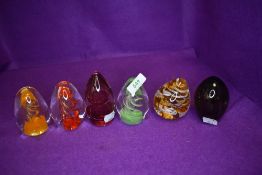A selection of art glass paper weights having swirl designs in orange and red tones