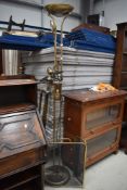 A vintage brass trifold fireguard and a modern reading lamp/uplighter