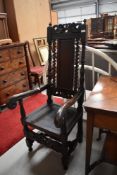 A traditional carved dark oak hall chair having solid seat and back , scroll arms and H stretcher