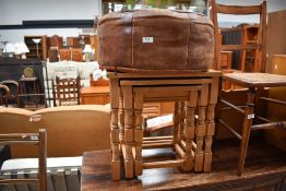 A light stained nest of three tables and a vintage leather pouffe